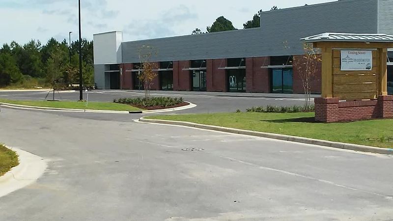 Low brick building with glass windows beside a curved paved driveway and grassy lawn