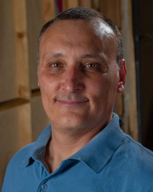 Portrait of a man in a blue polo shirt, looking at the camera with a slight smile.