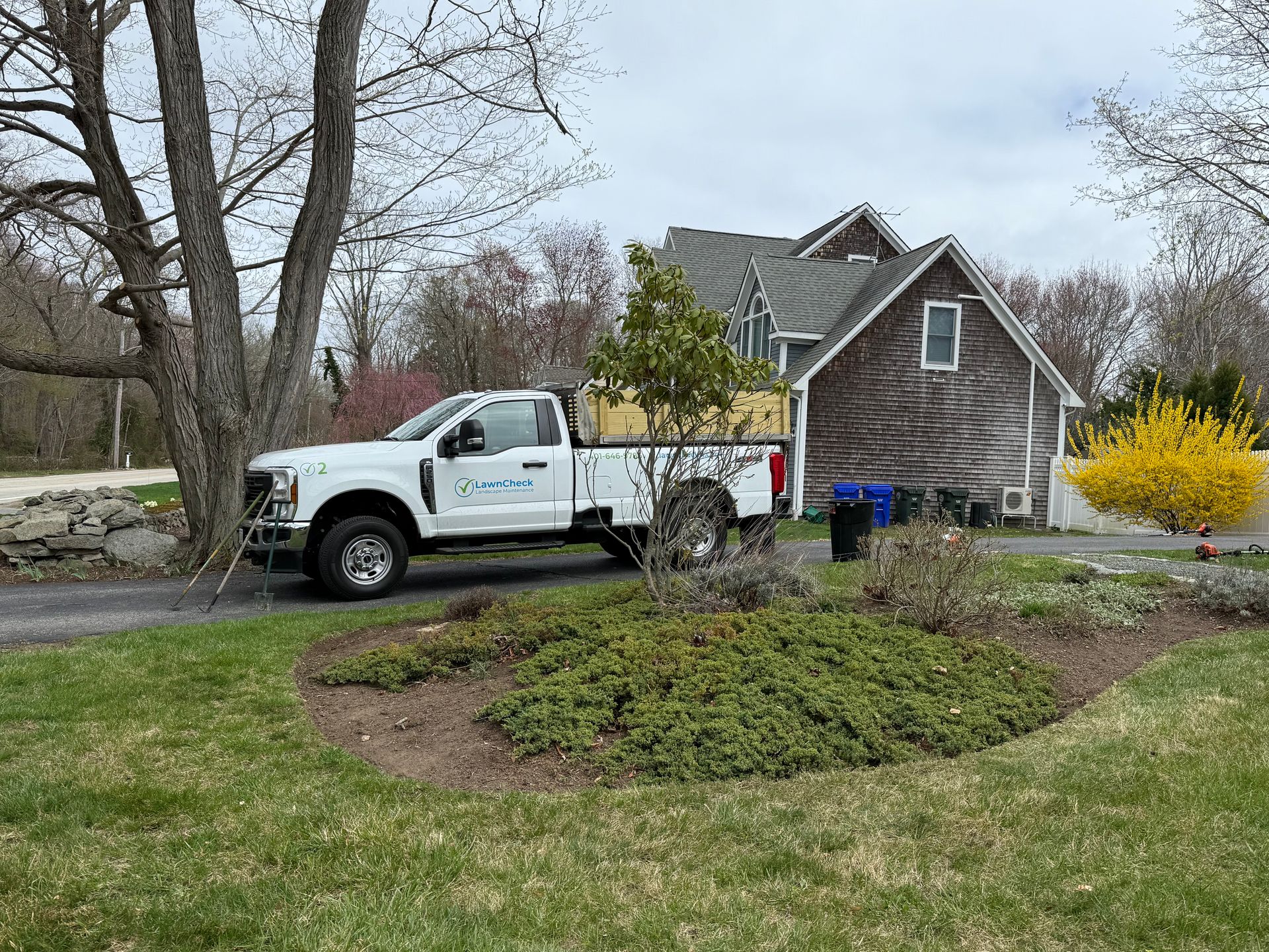 White utility truck parked by a house and landscaped front yard on a suburban street