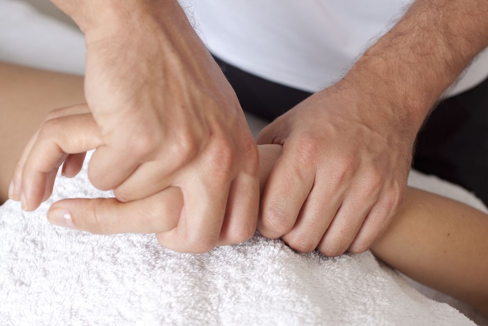 Hands Performing Massage on a Forearm Resting on a White Towel — Grays Chiropractic & Wellness In Ooralea, QLD