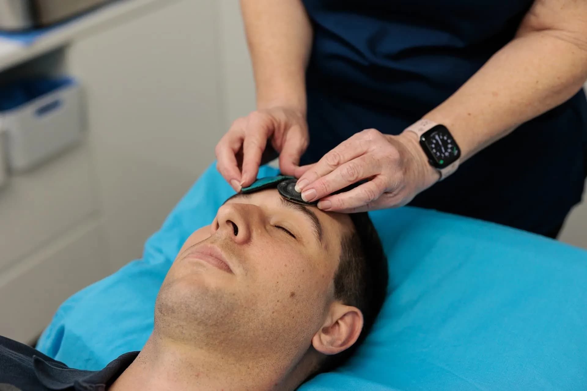Person Getting Forehead Treatment, Eyes Closed, While Someone Applies Pads — Grays Chiropractic & Wellness In Paget, QLD