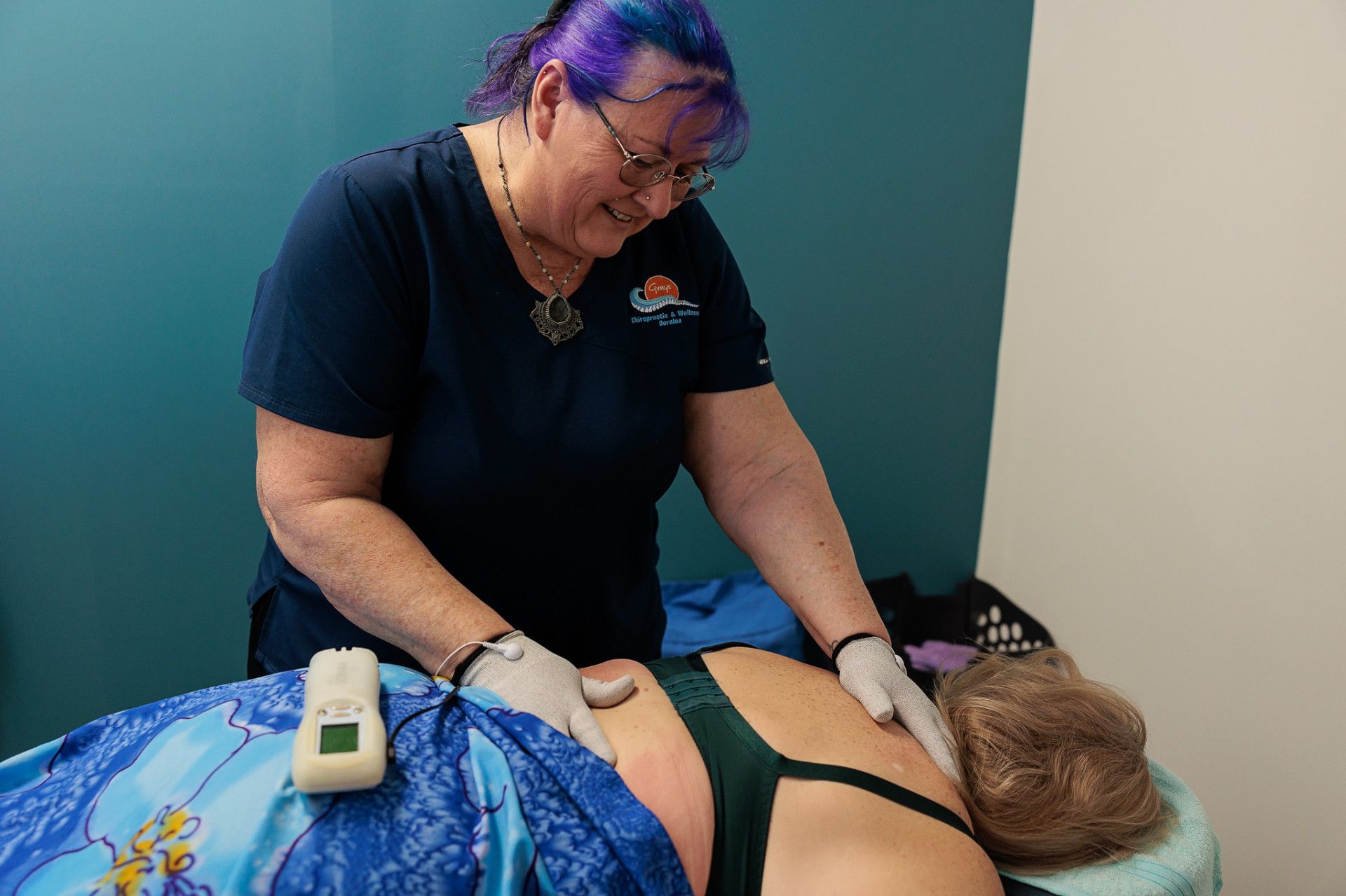 A Medical Professional in Scrubs Examining a Patient's Back with A Device in A Clinic — Grays Chiropractic & Wellness In Ooralea, QLD