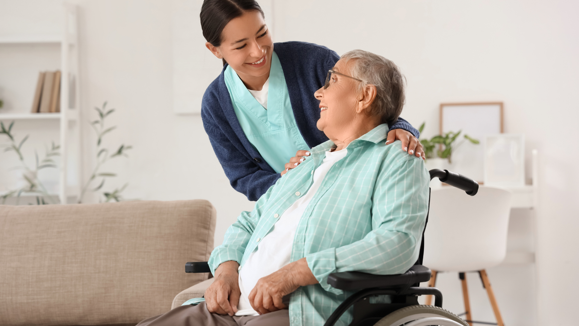 Caregiver smiling and speaking with a seated patient in a bright living room