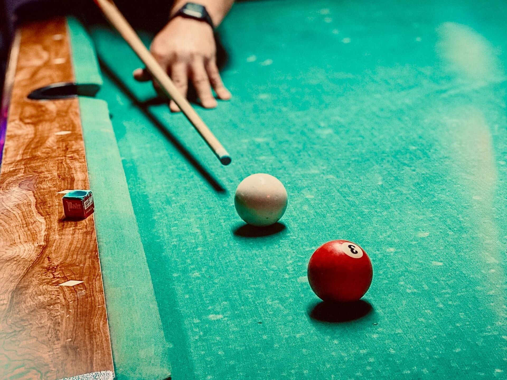 A person is playing pool on a pool table representing our pool table repair services.