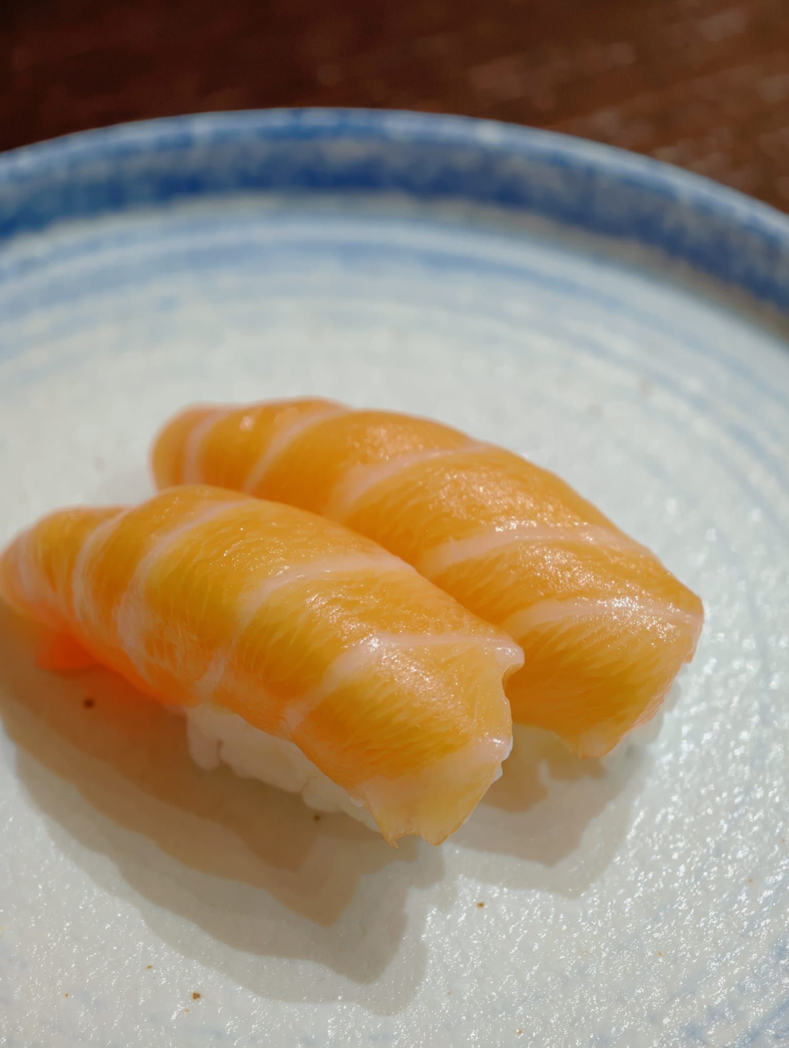 Due nigiri di salmone su un piatto bianco con il bordo blu