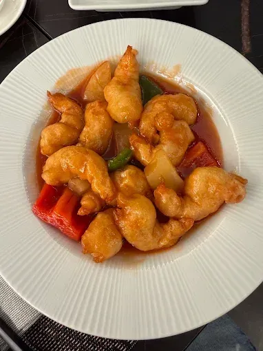 Piatto di gamberi dorati fritti in salsa agrodolce con peperoni rossi e verdi
