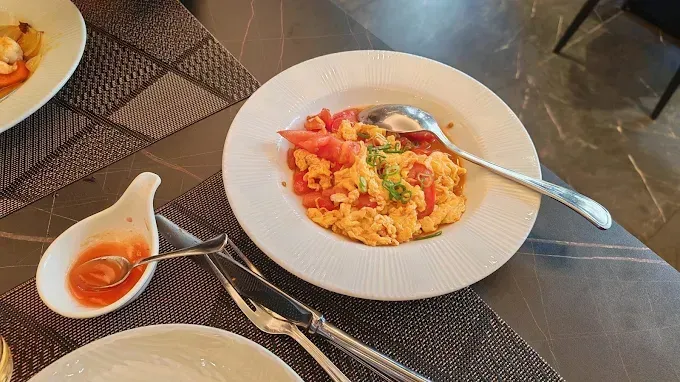 Piatto di pasta al pomodoro su un piatto bianco, con un cucchiaio appoggiato accanto su un tavolo da caffè