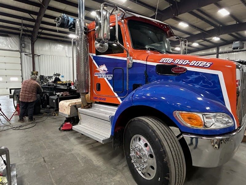 A red and blue tow truck is parked in a garage.