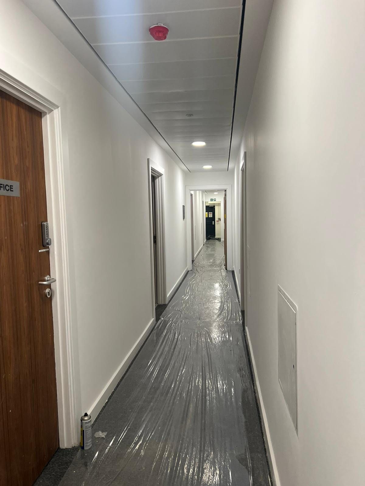 A long hallway in a building with plastic covering the floor.