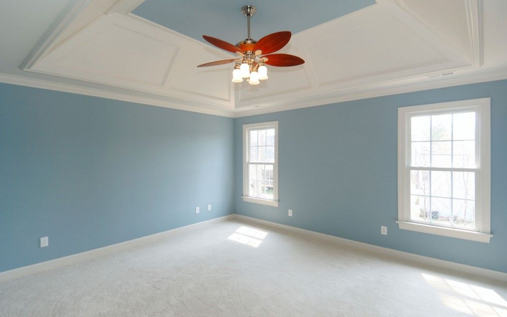 An empty room with blue walls and a ceiling fan