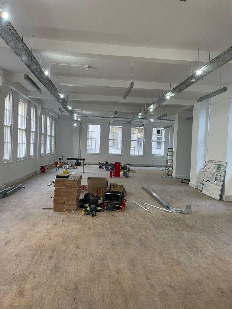 A large empty room with a lot of windows and boxes on the floor.