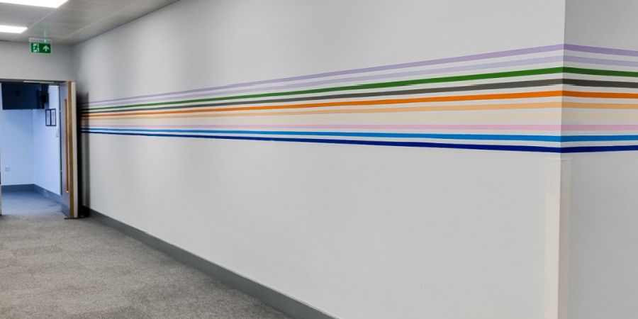 A long hallway with a colorful stripe on the wall