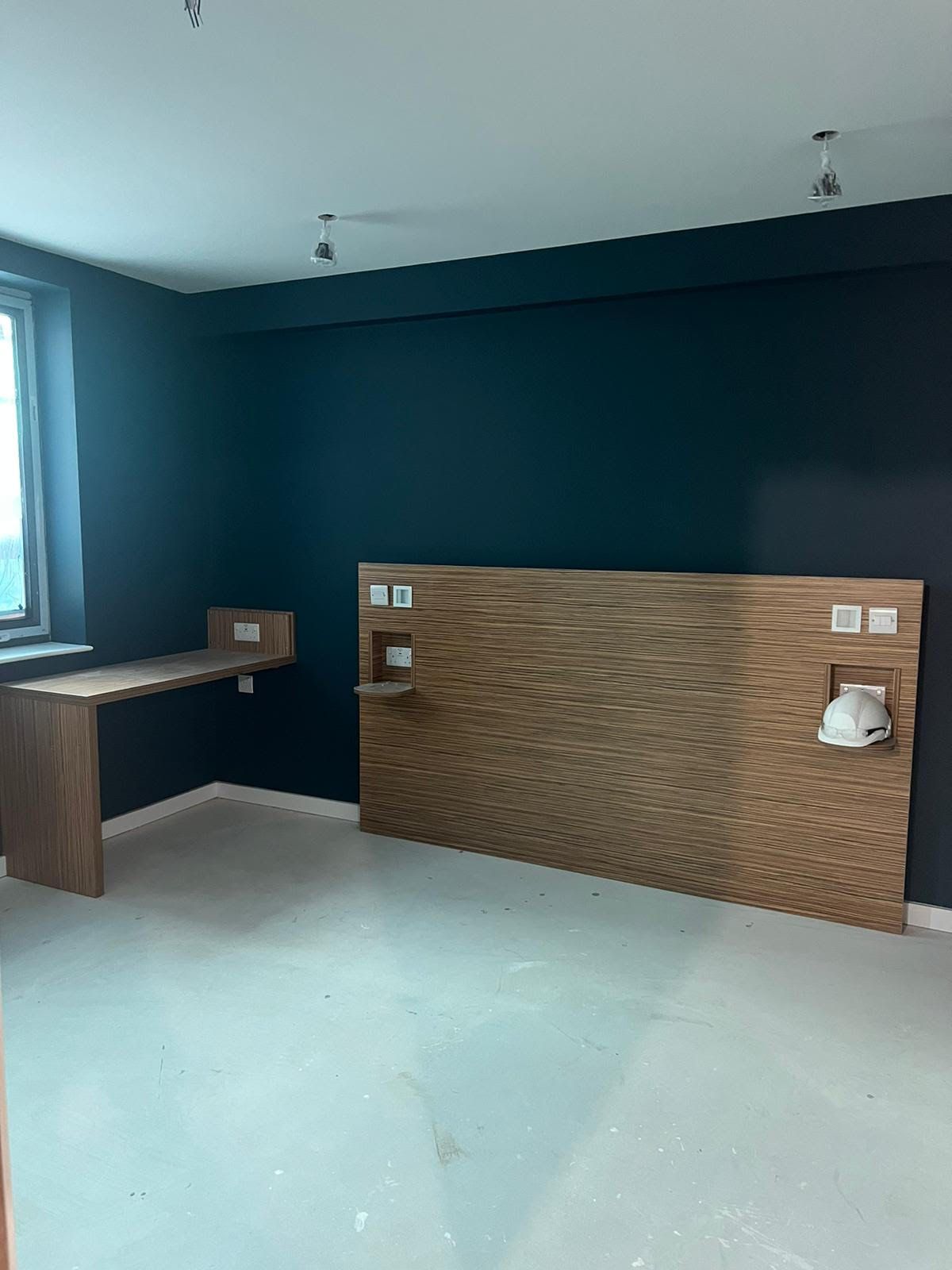 An empty room with a wooden headboard and a desk.