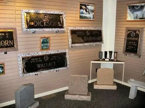 Room with headstones and plaques on display in a memorial shop, light brown walls.