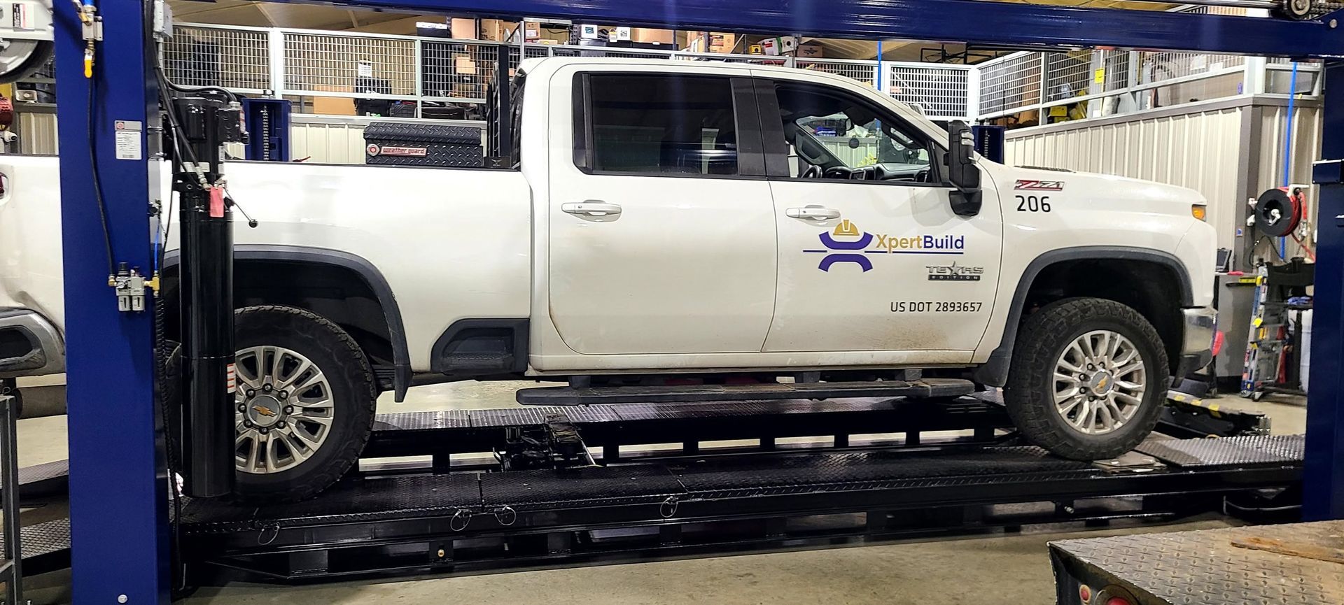 White pickup truck on a hydraulic lift in an auto repair shop
