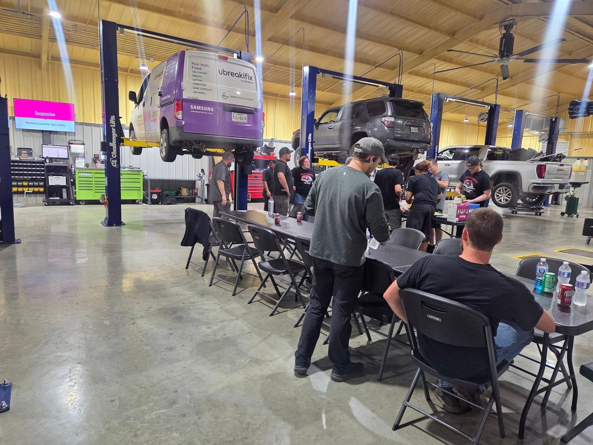 People seated at a large indoor expo hall with cars on display and booths in the background