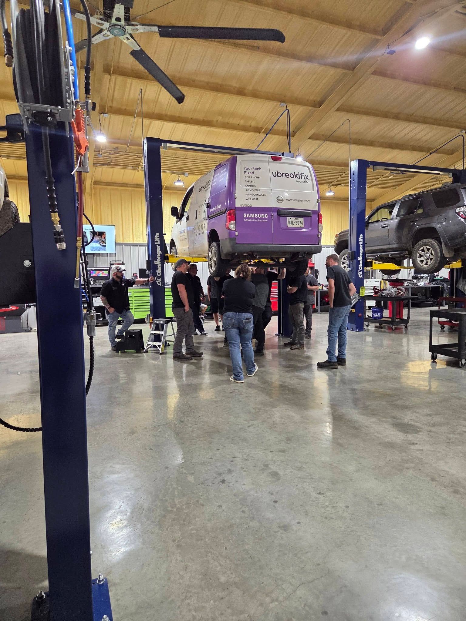 Auto repair shop with cars lifted on hydraulic lifts and mechanics working underneath.