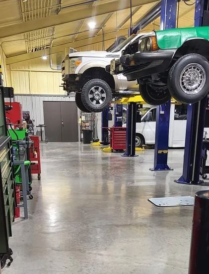 Off-road vehicle lifted on a shop hoist inside an auto repair garage