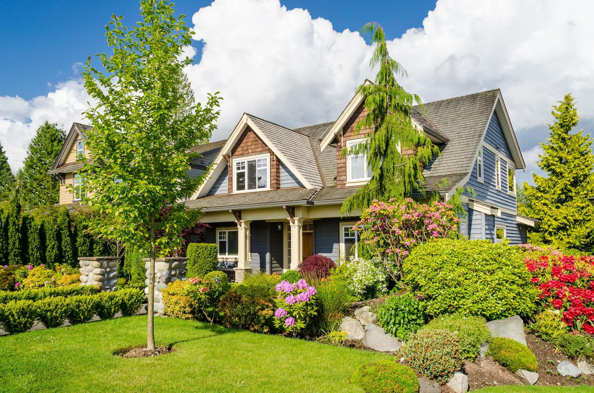 A large house with a lush green lawn and trees in front of it.