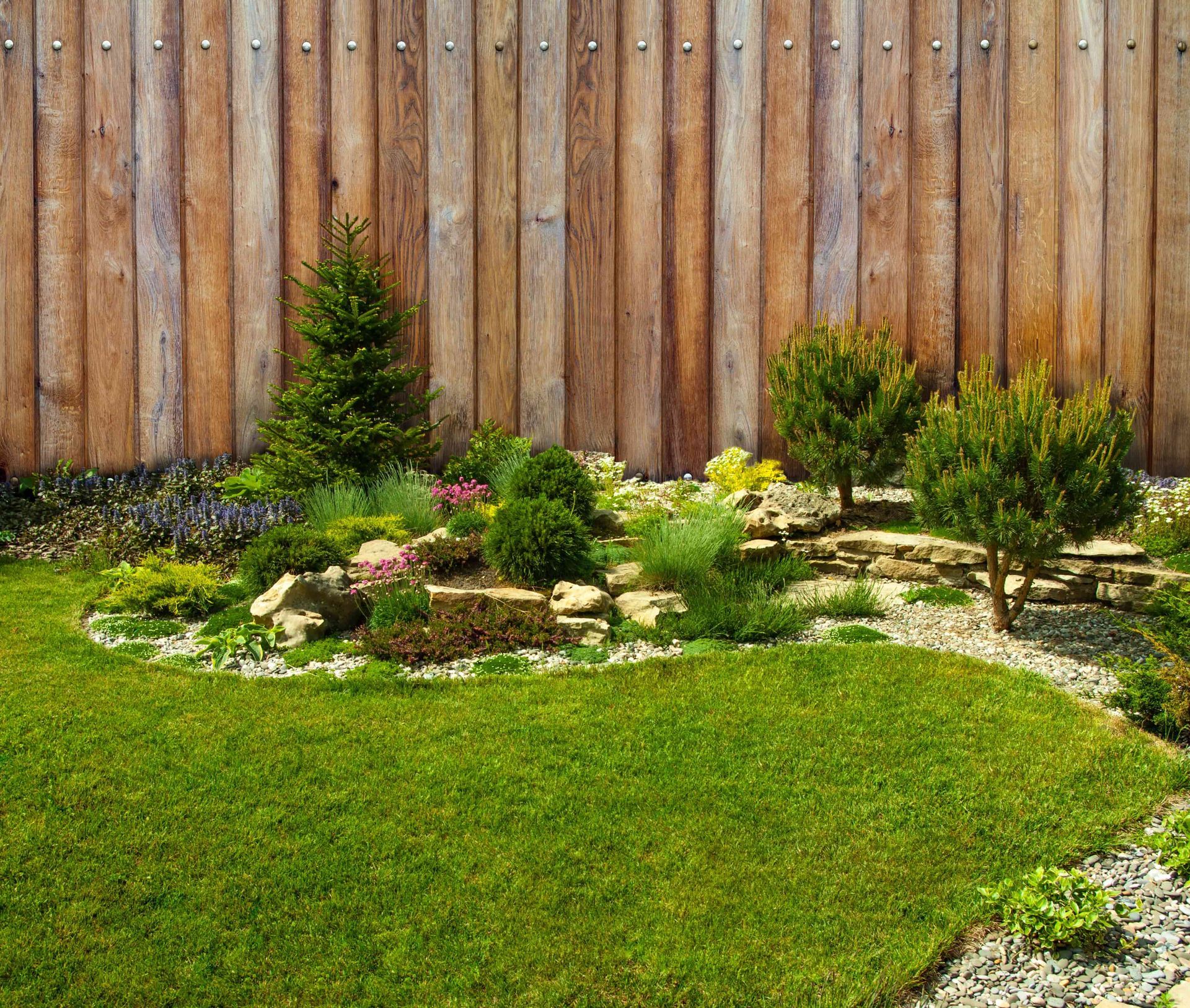 A wooden fence surrounds a lush green garden.