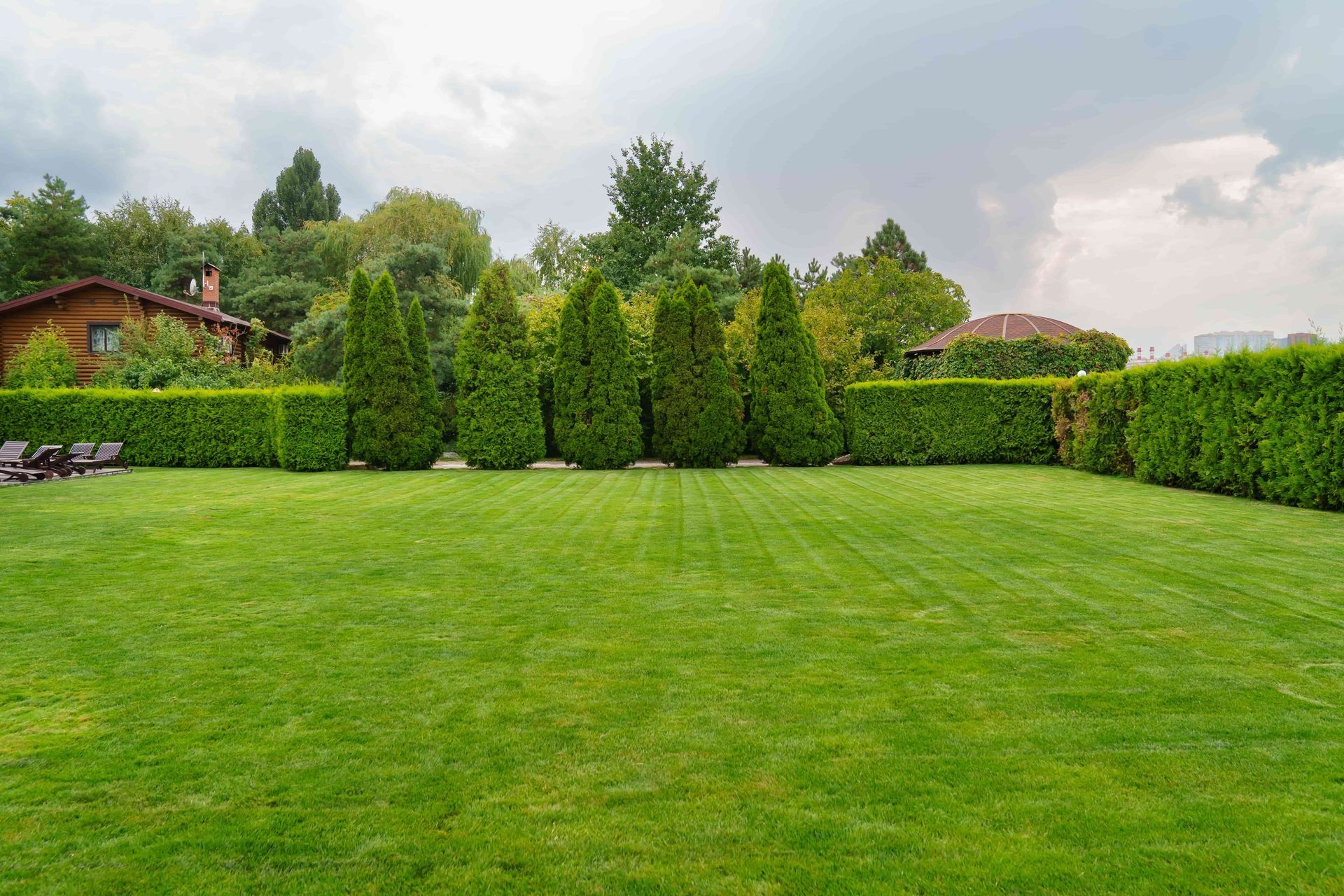 A large lush green lawn with trees and bushes in the background.