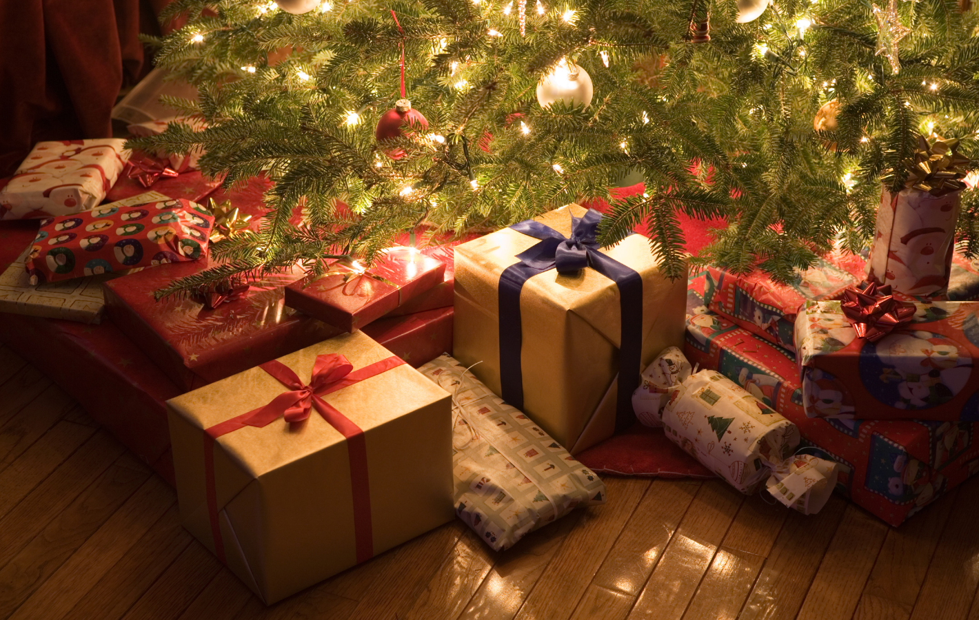 Gifts wrapped and placed under a decorated Christmas tree.