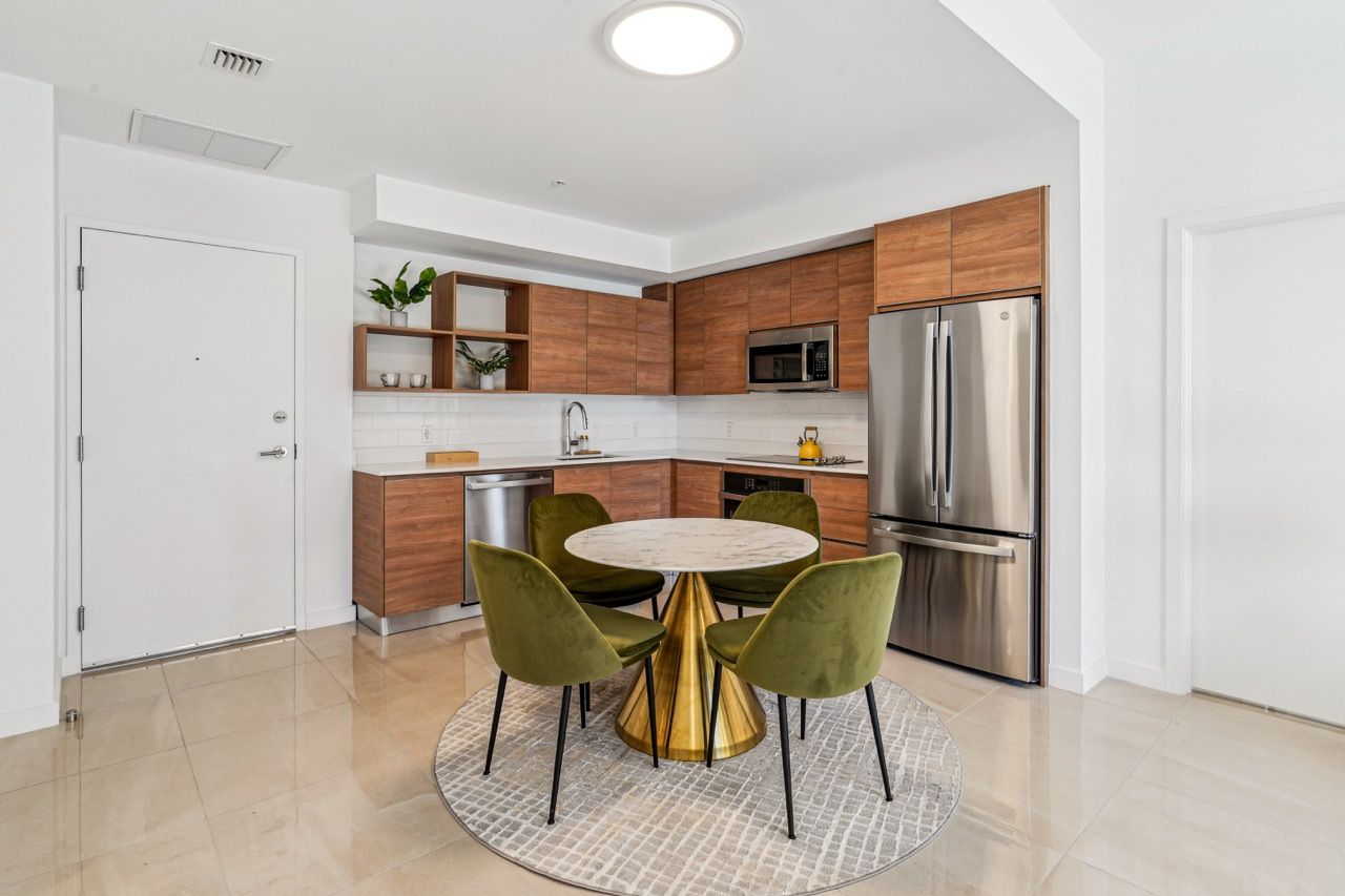 Modern kitchen with wood cabinets, stainless steel appliances, and a round marble dining table.