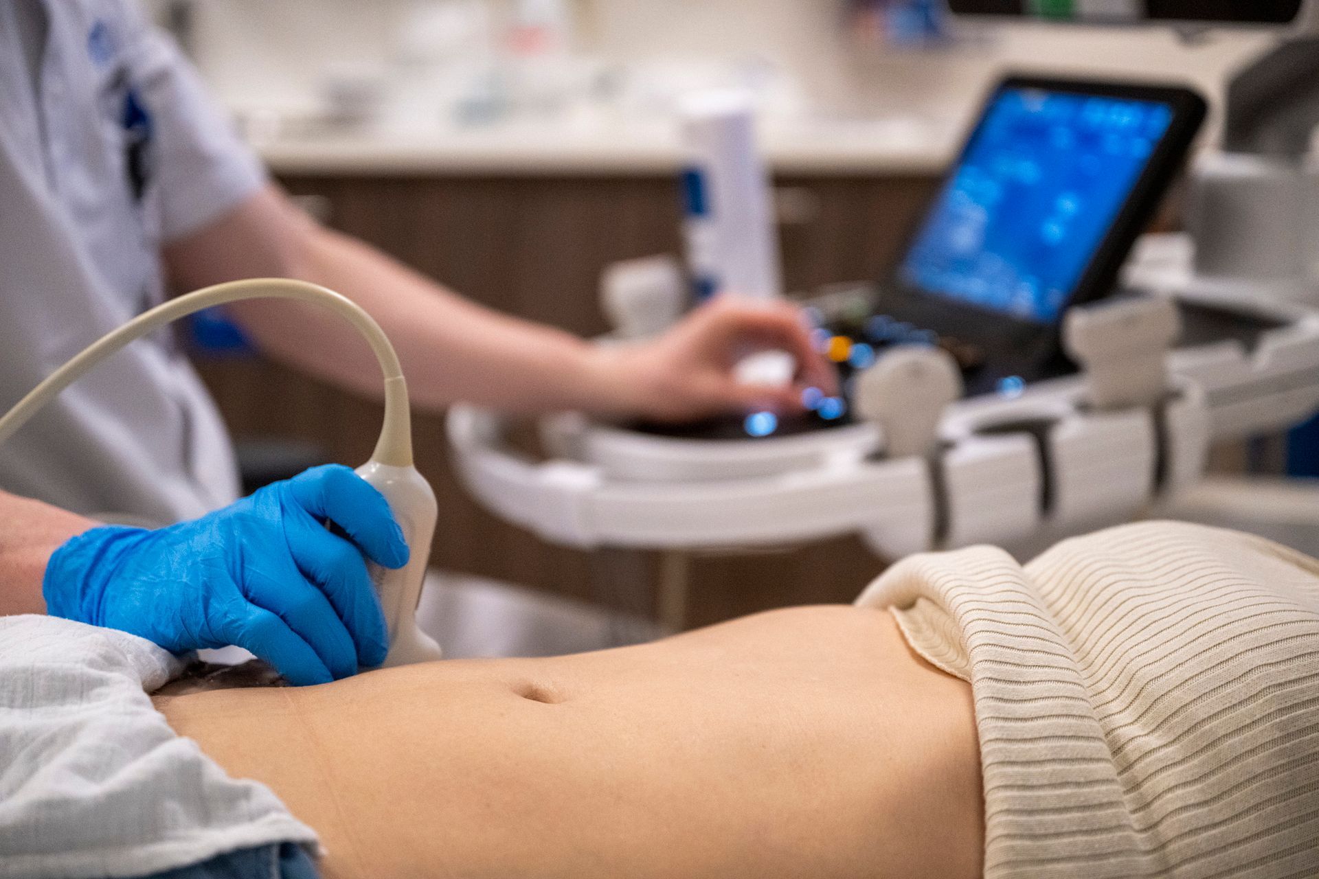 A person wearing blue gloves is holding a swab and a test tube.