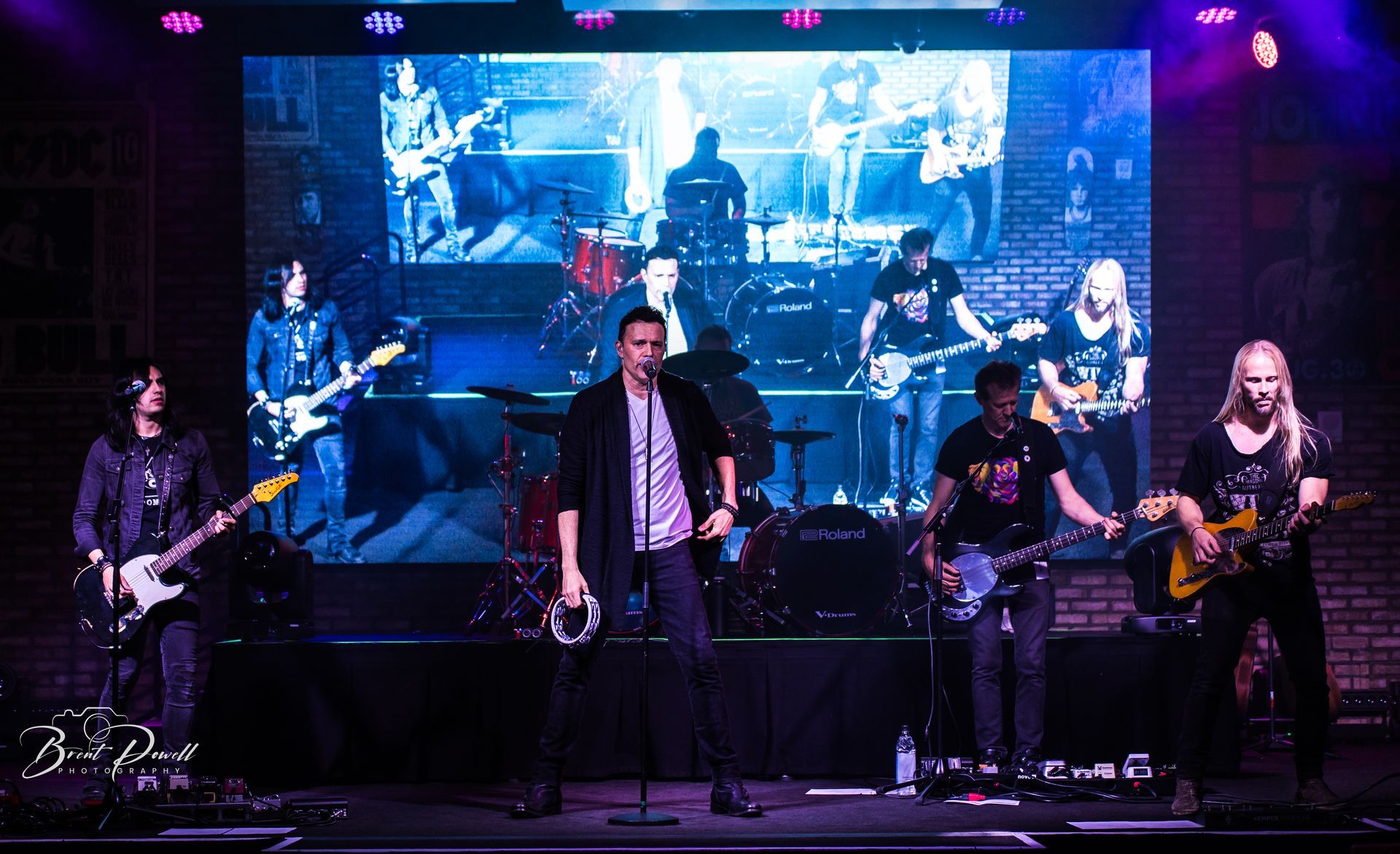 A group of people are playing instruments on a stage in front of a large screen.