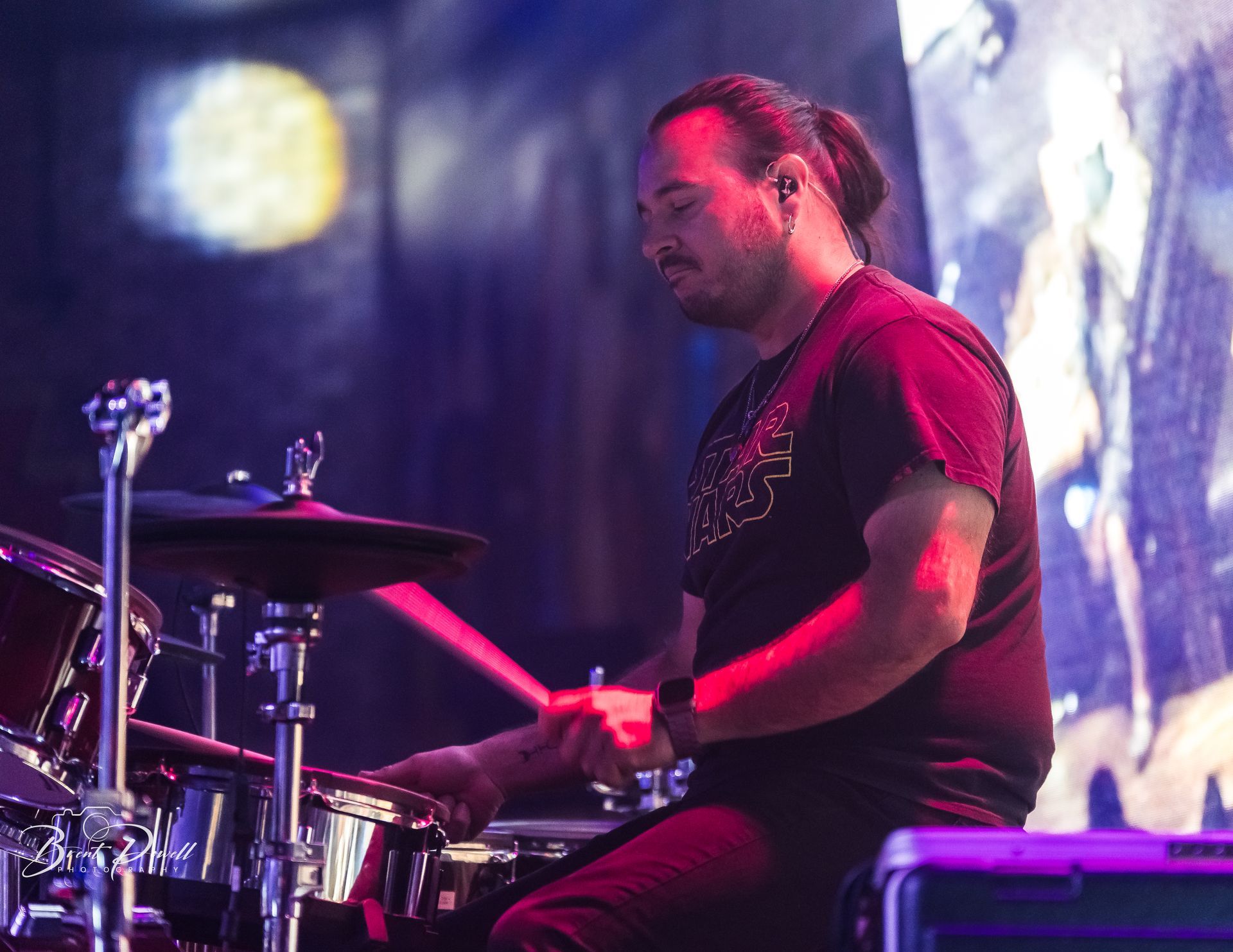 A man in a black shirt is playing drums on a stage