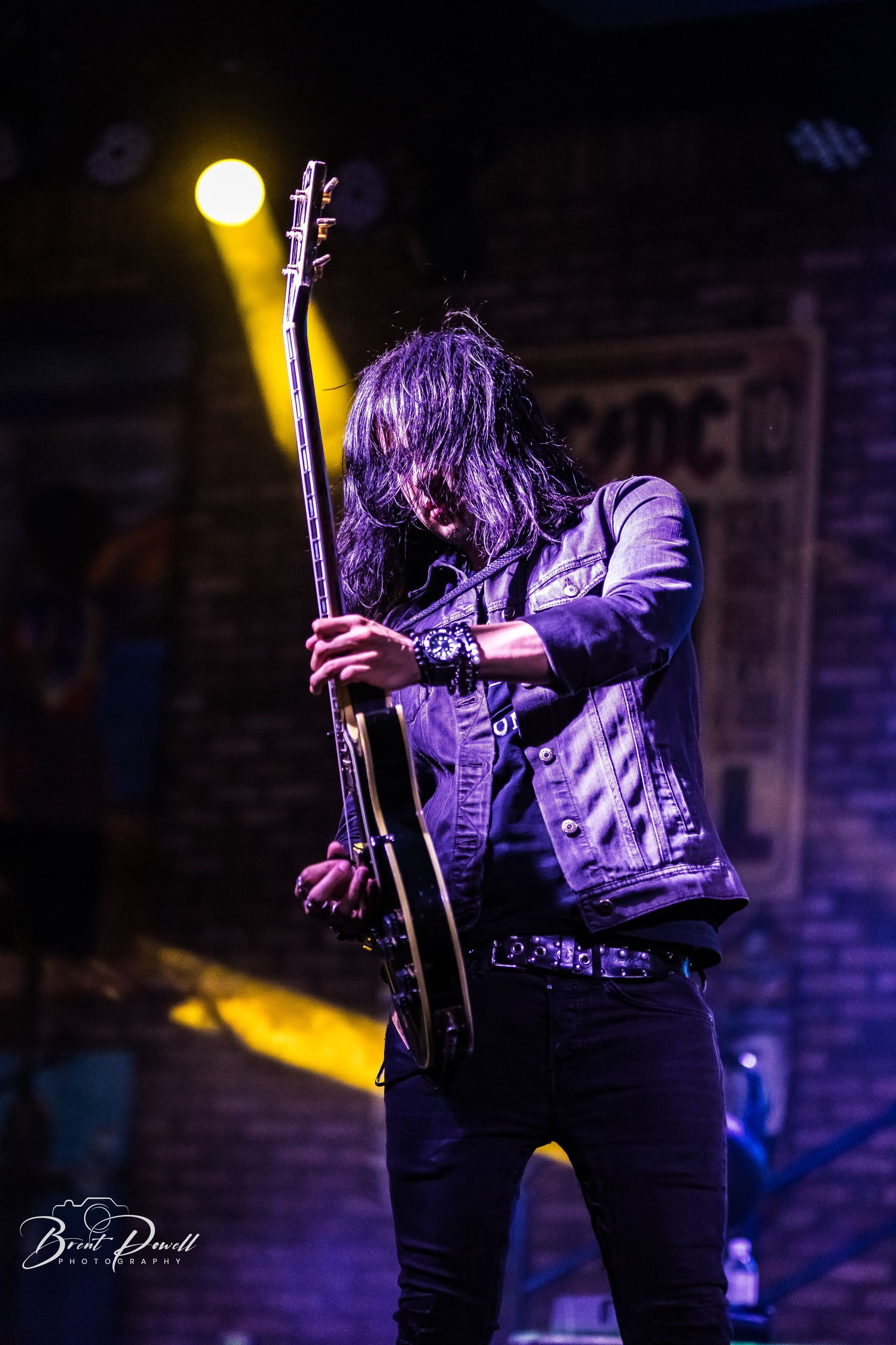 A man with long hair is playing a guitar on a stage.