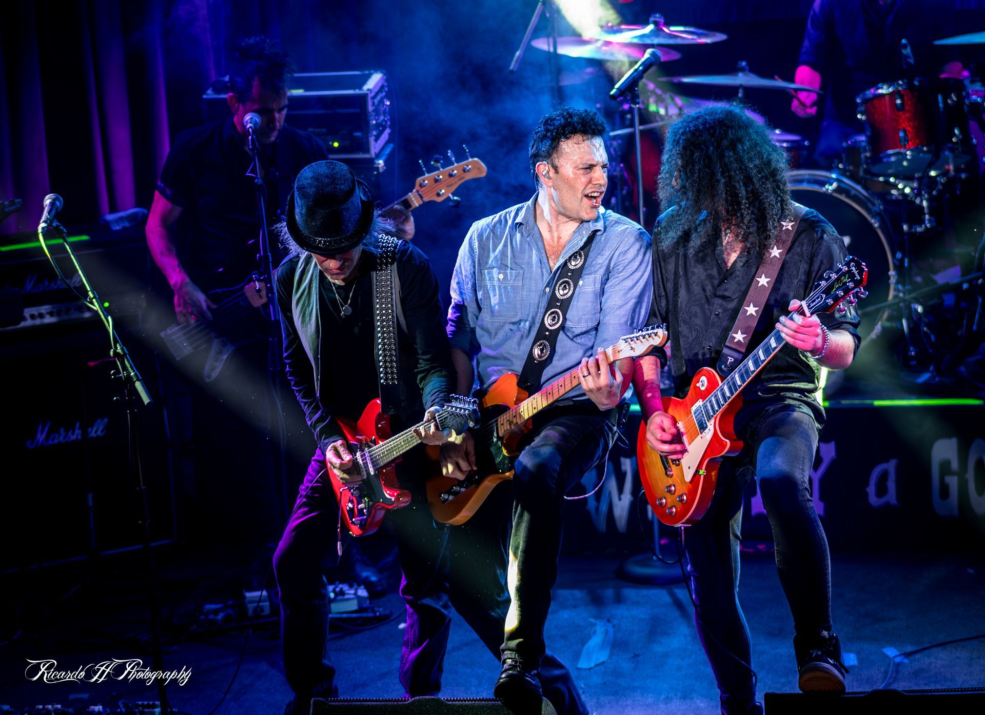 A group of men are playing guitars on a stage.