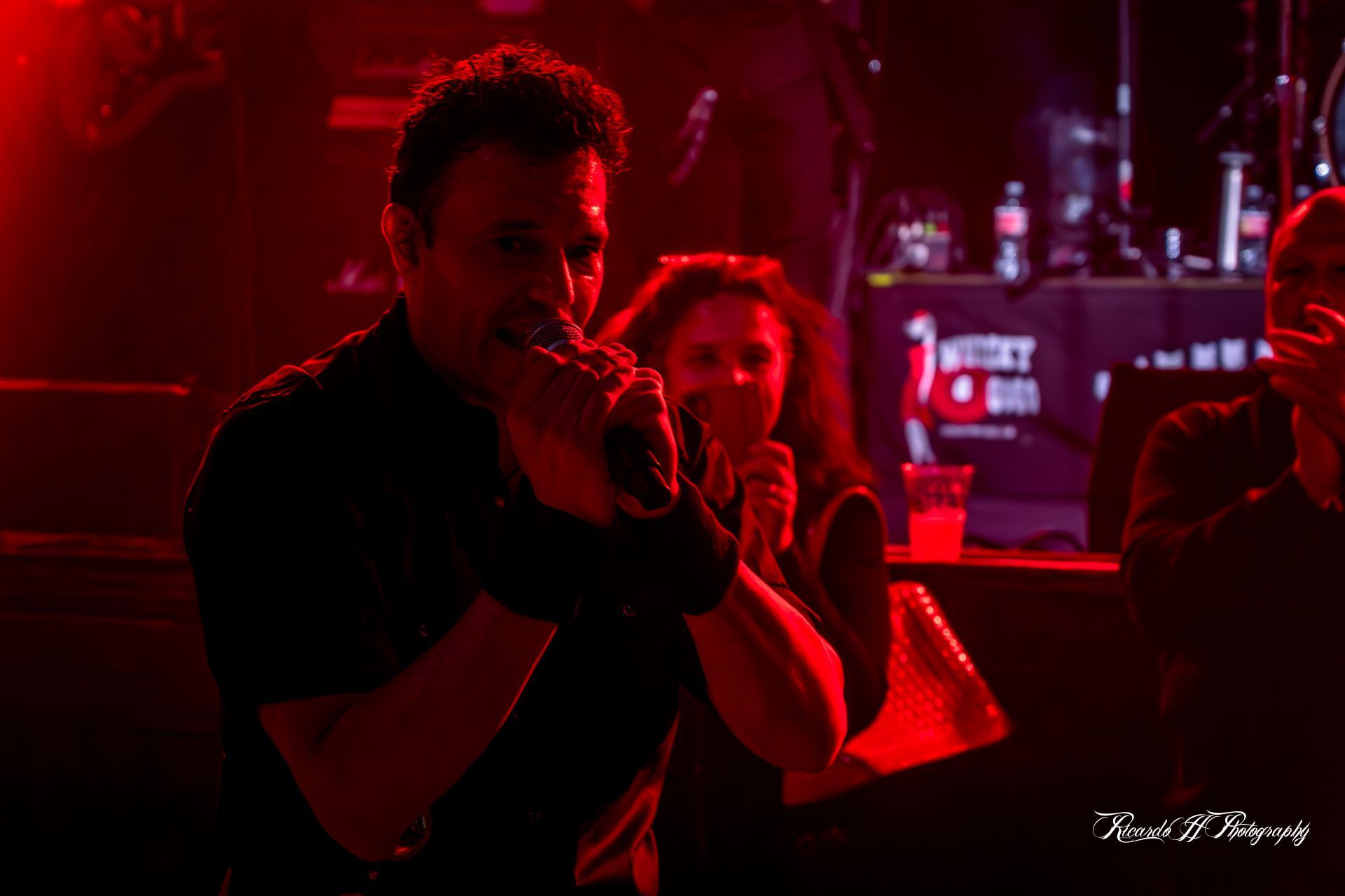 A man is singing into a microphone in a dark room.