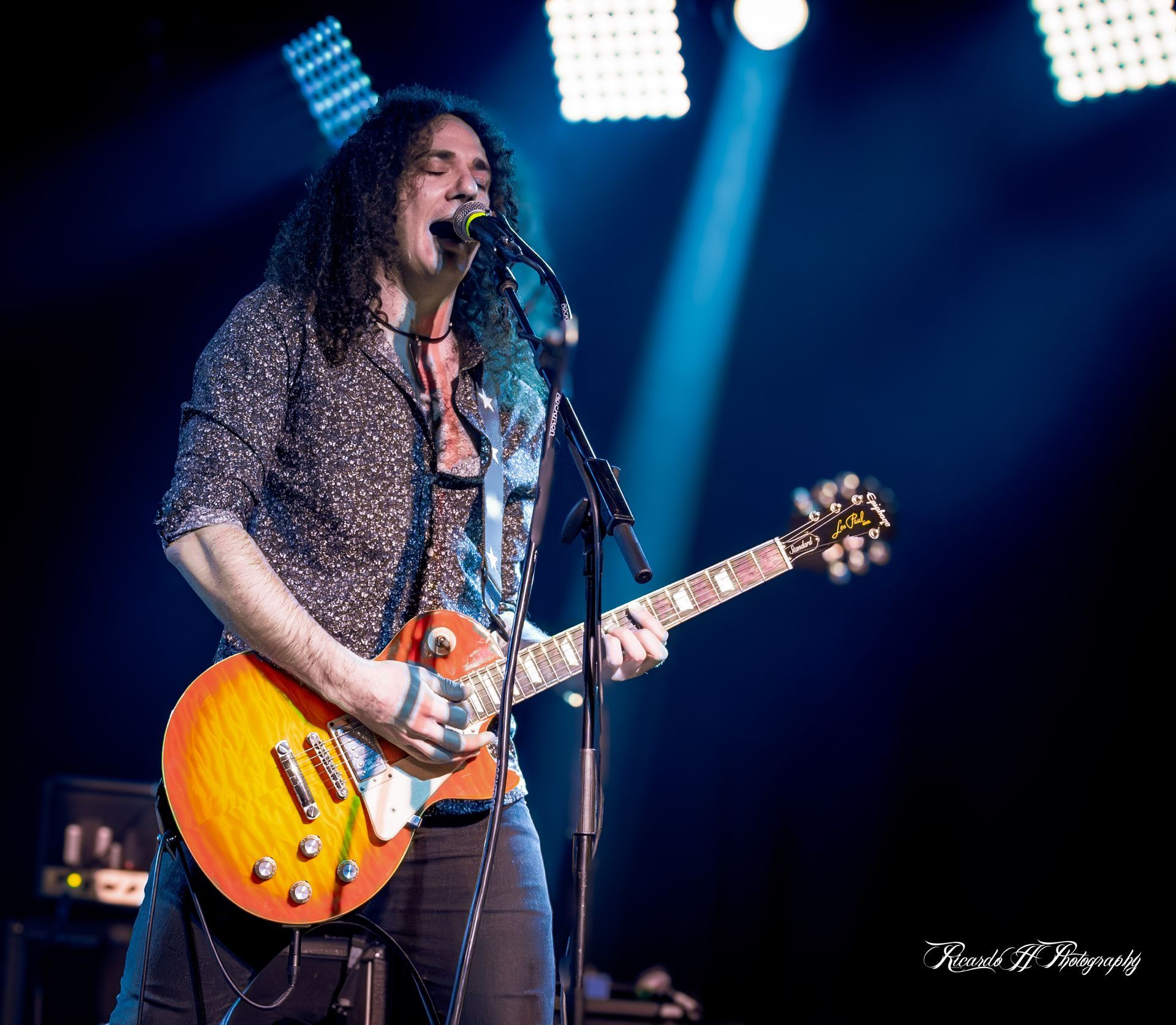 A man singing into a microphone while playing a guitar