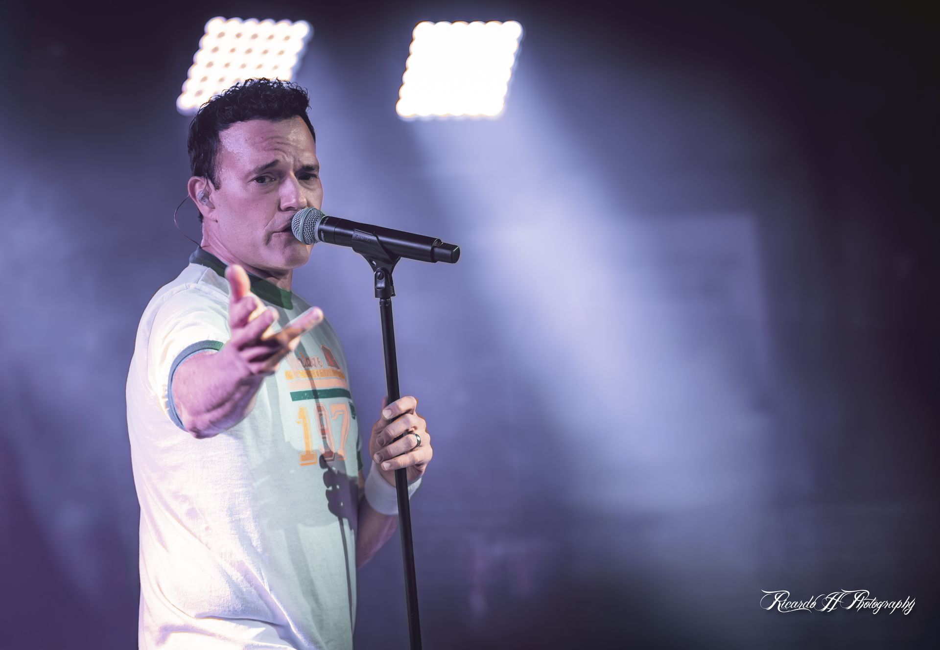 A man is singing into a microphone on a stage.
