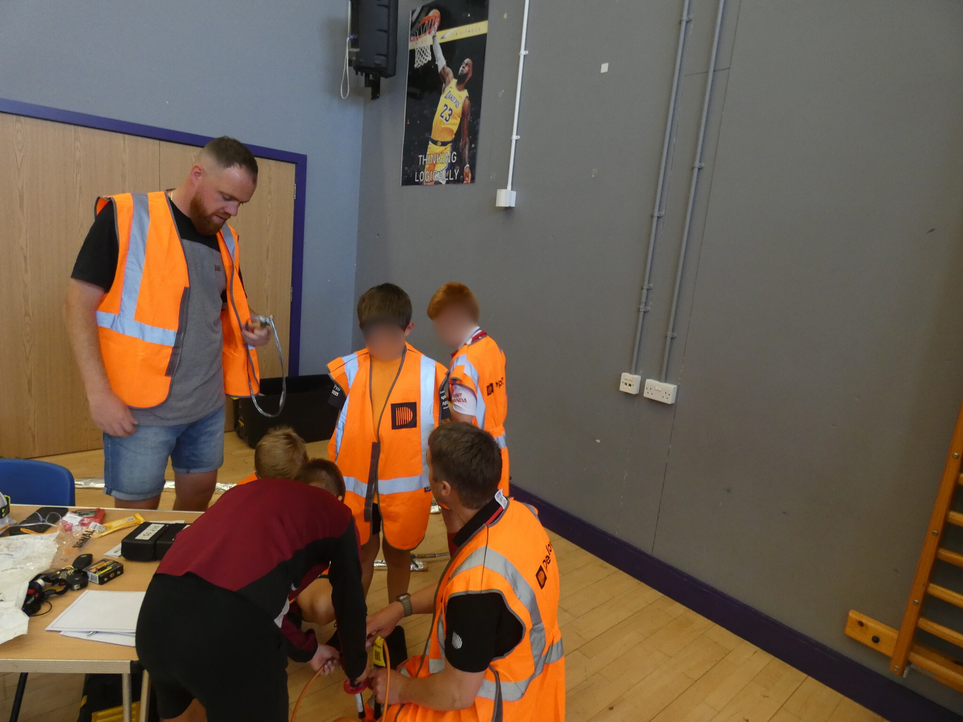 People in orange vests assess children indoors.