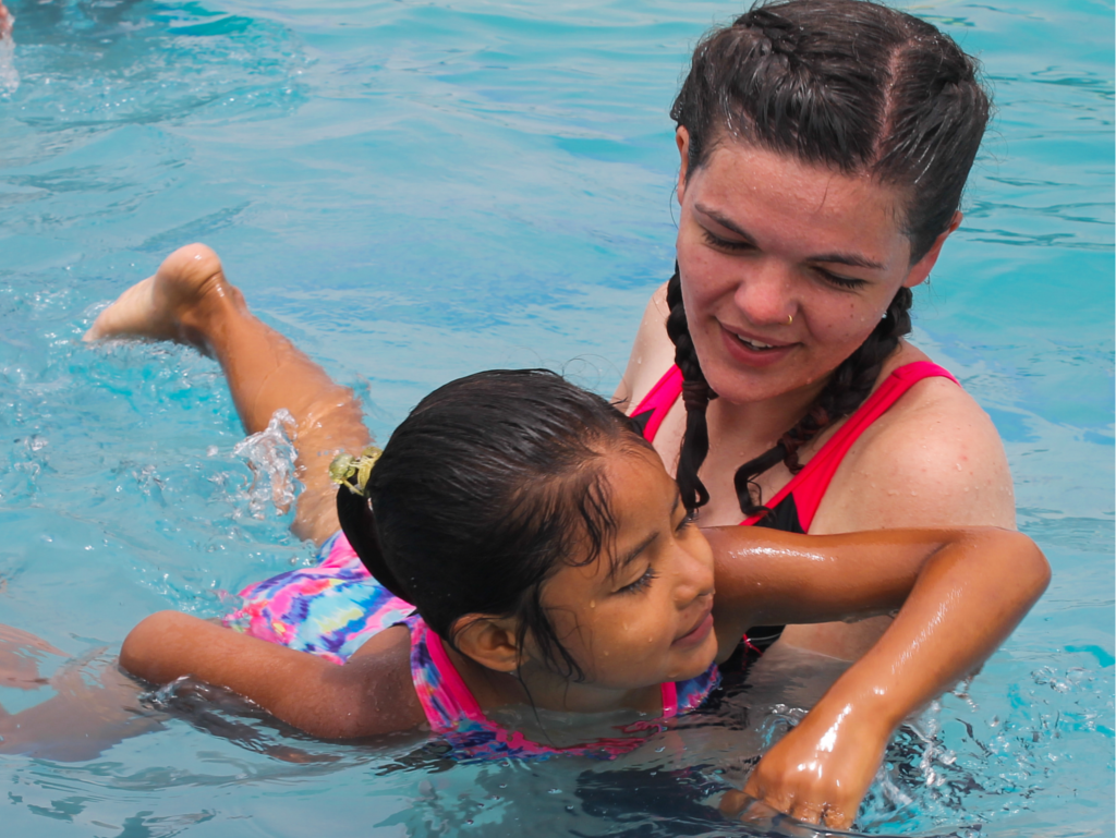 An Otra Cosa volunteer teaches a local child how to swim.