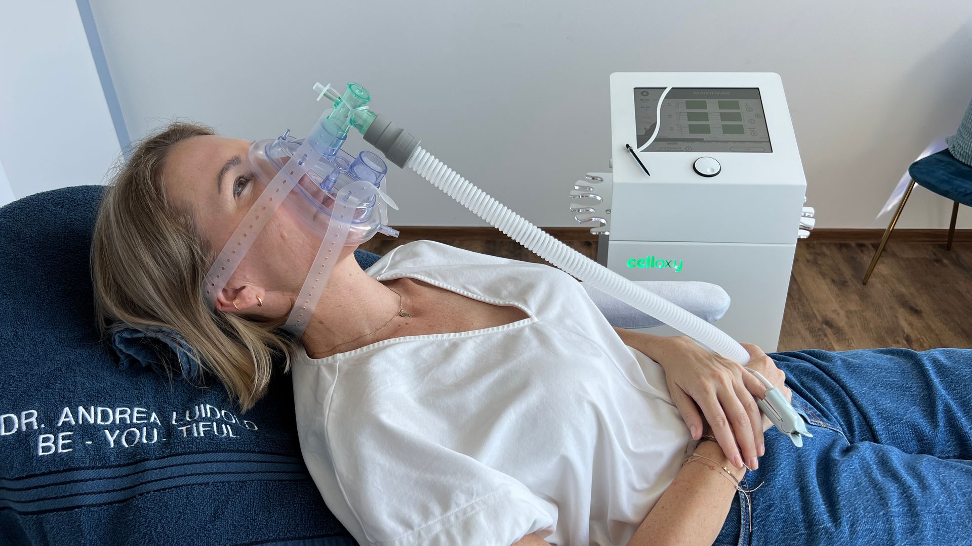Frau liegt mit einer Sauerstoffmaske liegend bei IHHT-Behandlung und ist an eine weiße Maschine angeschlossen.