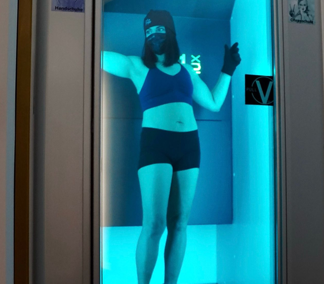 Person in der Kryotherapiekammer mit Maske, das Logo „Art of Cryo“ ist sichtbar.