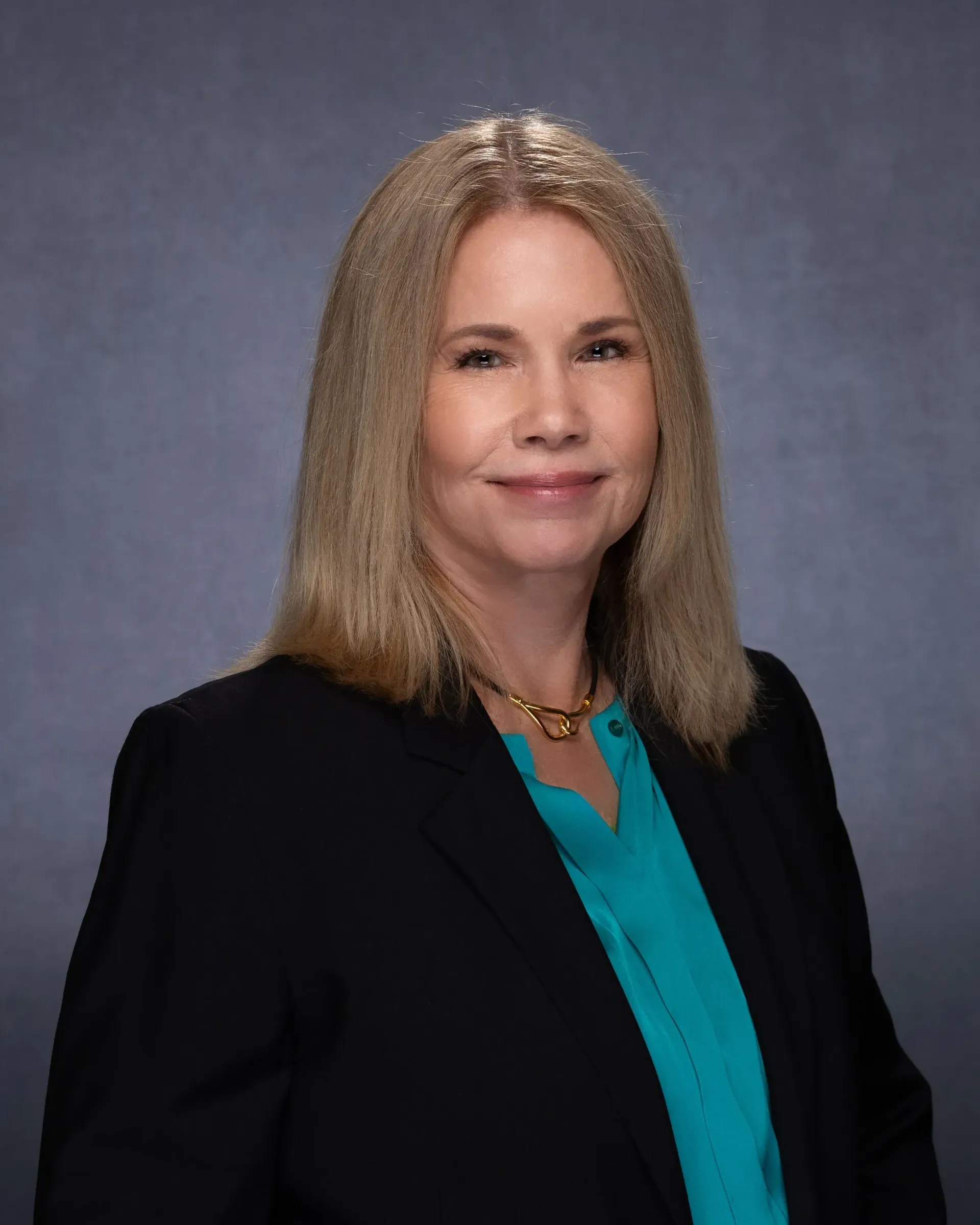 Attornye Jennifer C. Harrington in a black blazer and teal blouse, smiling, against a gray background.