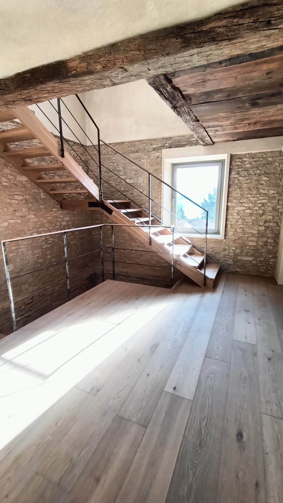 Mansarda rustica vuota con travi in ​​legno, scala, pavimento bianco e finestra.