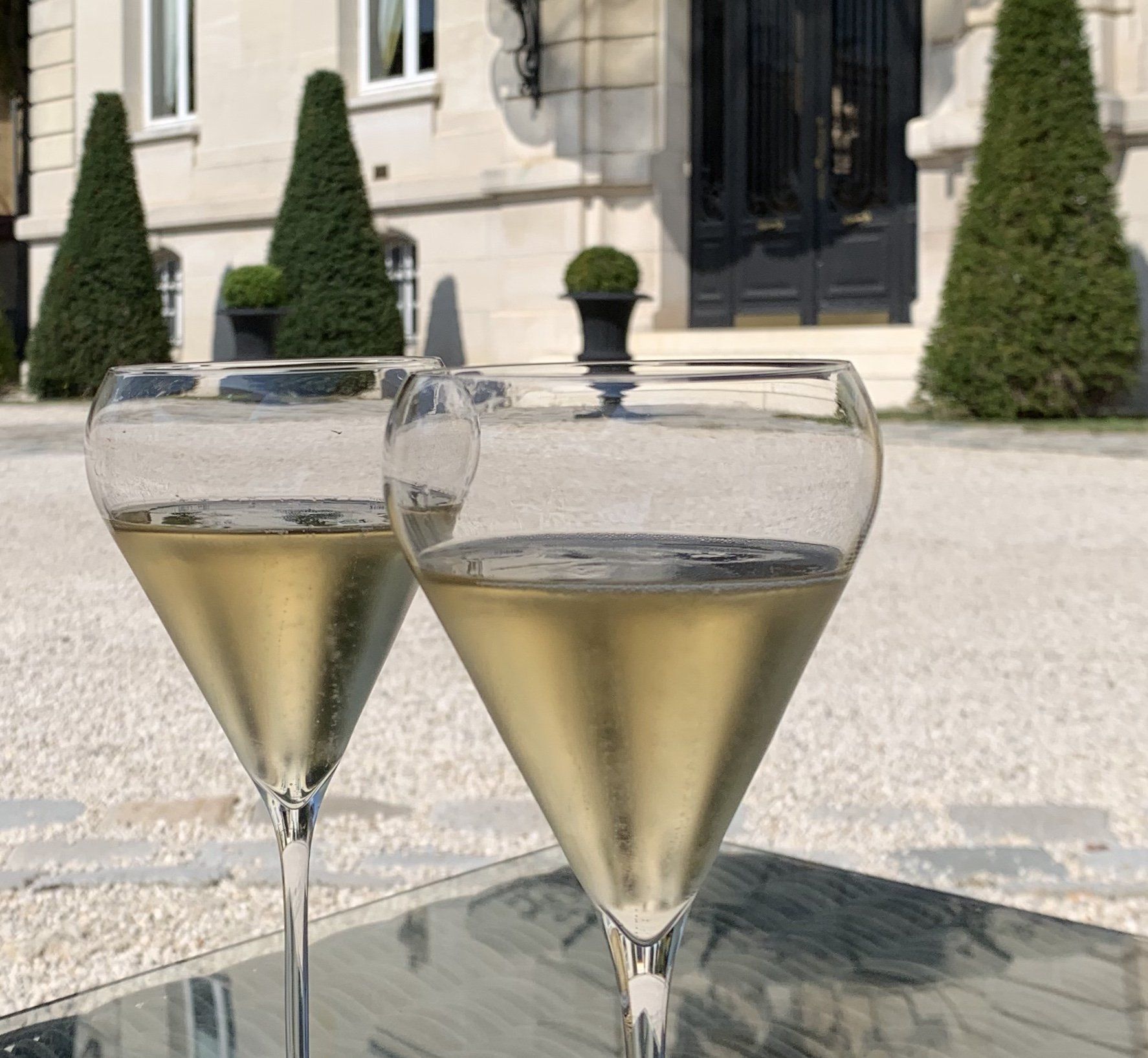 Zwei Gläser Champagner stehen auf einem Tisch vor einem Gebäude.