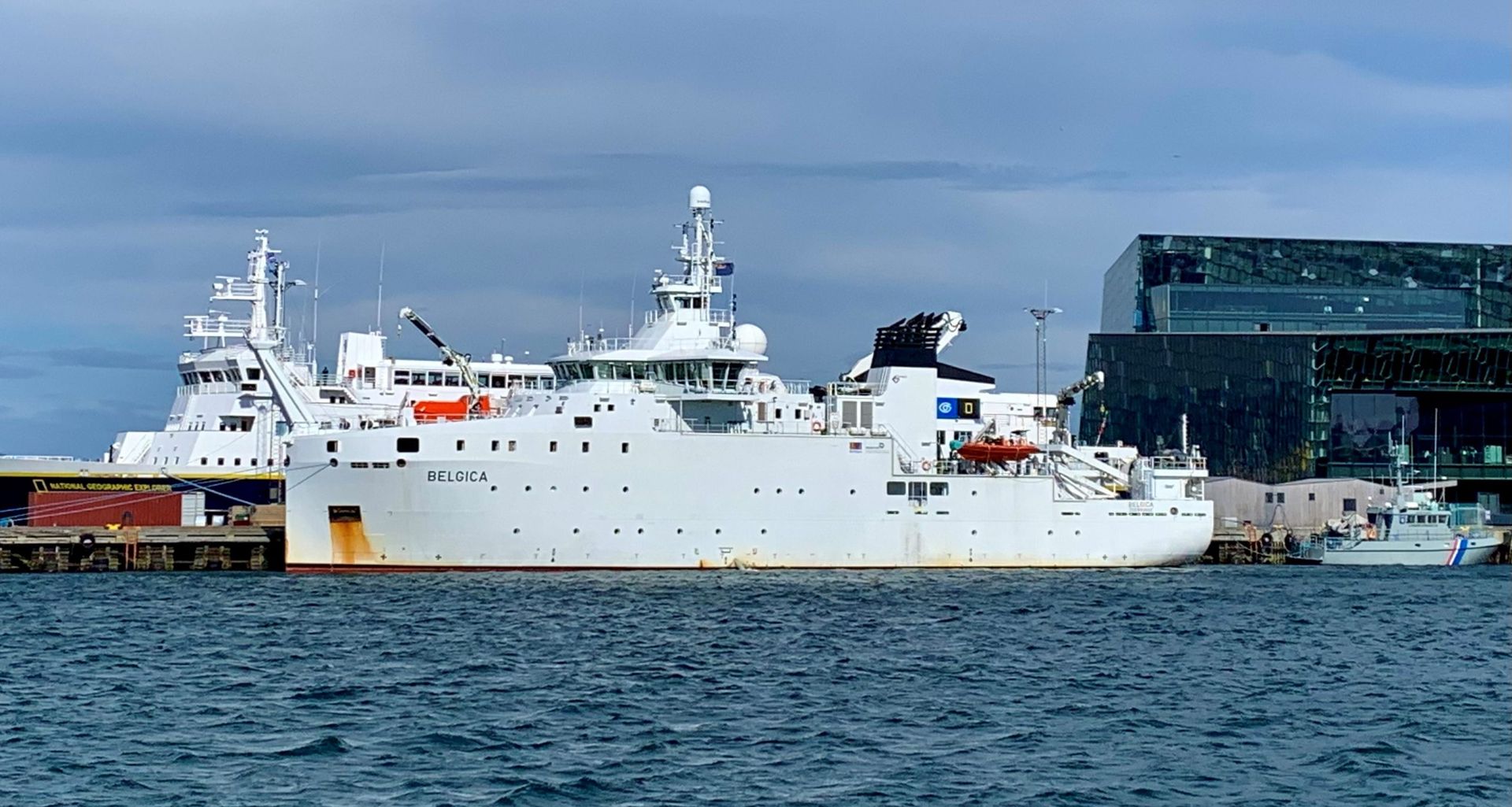 Ein großes weißes Schiff liegt im Wasser in der Nähe eines Gebäudes