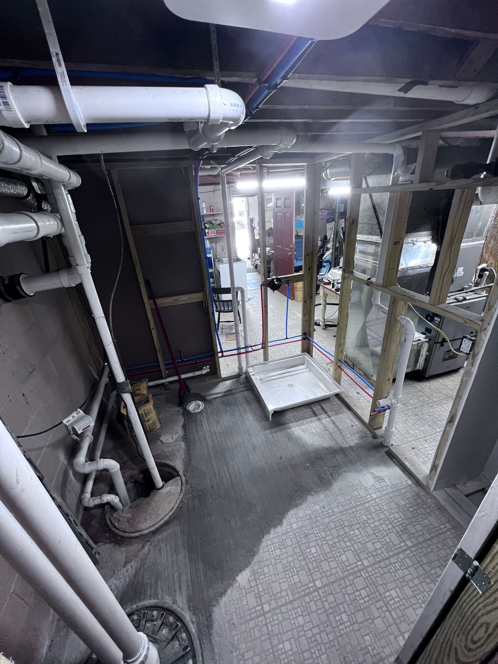 Basement with plumbing and unfinished walls. A metal ramp and doorway lead to a brighter space.