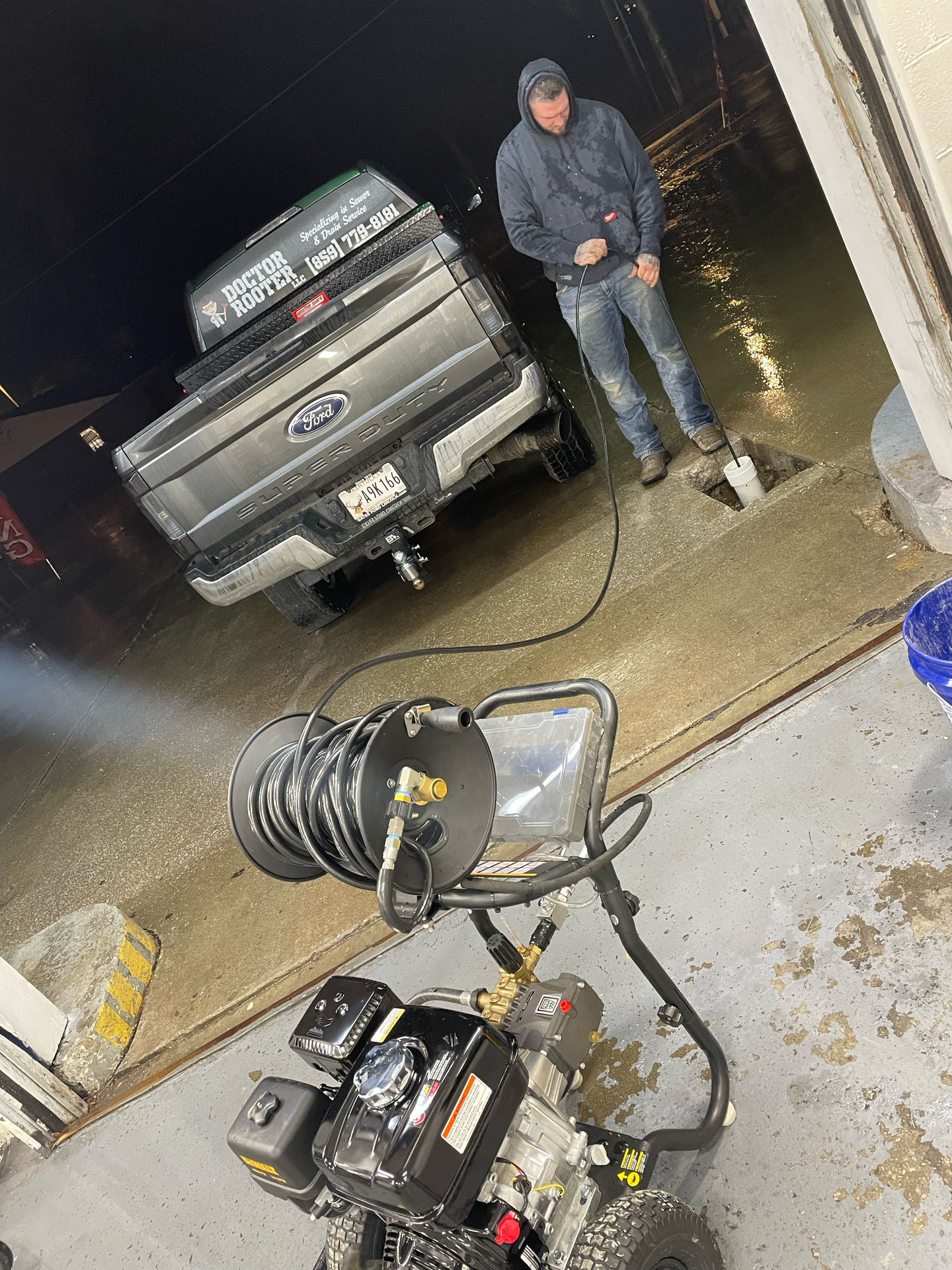 Man power washing a gray pickup truck at night with a pressure washer.