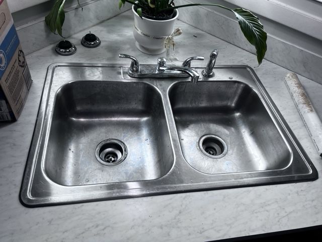 Stainless steel double sink in a kitchen corner.