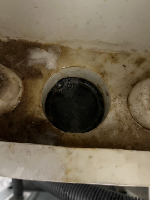 Black drain plug inside a dirty, white compartment.