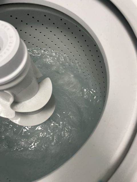 Washing machine tub with water swirling around the agitator, preparing to wash clothes.