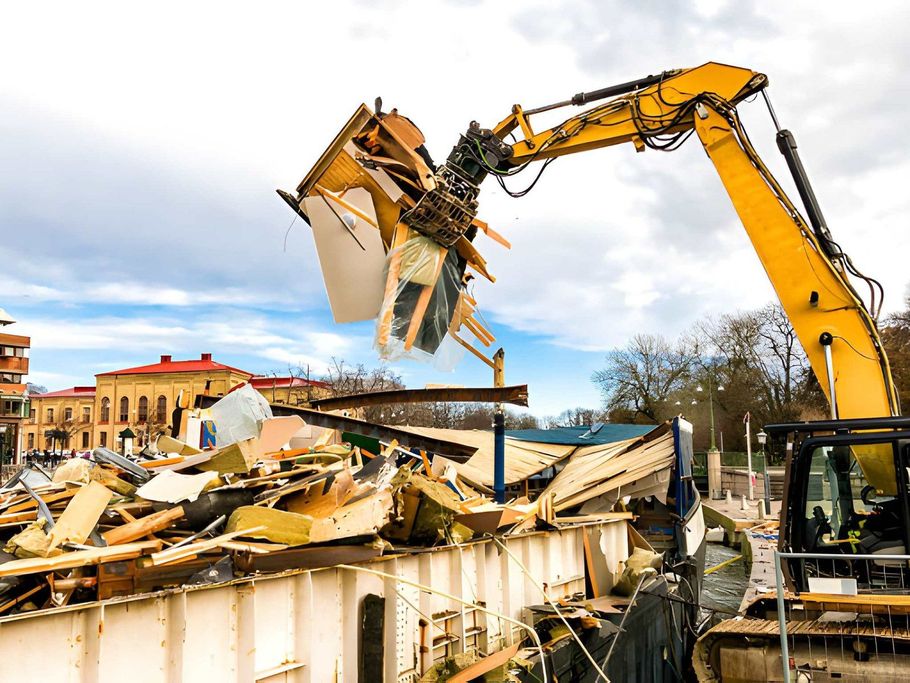 Yellow excavator demolishing a building, lifting debris at a construction site