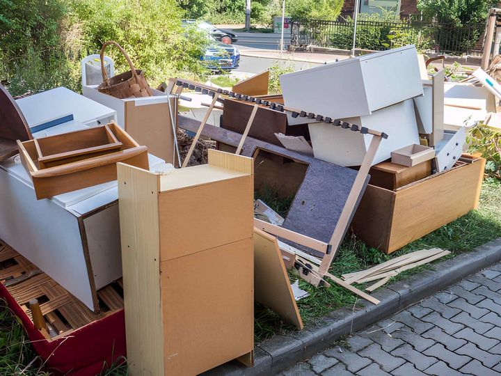 Pile of discarded cardboard boxes and furniture on a sidewalk beside a grassy curb